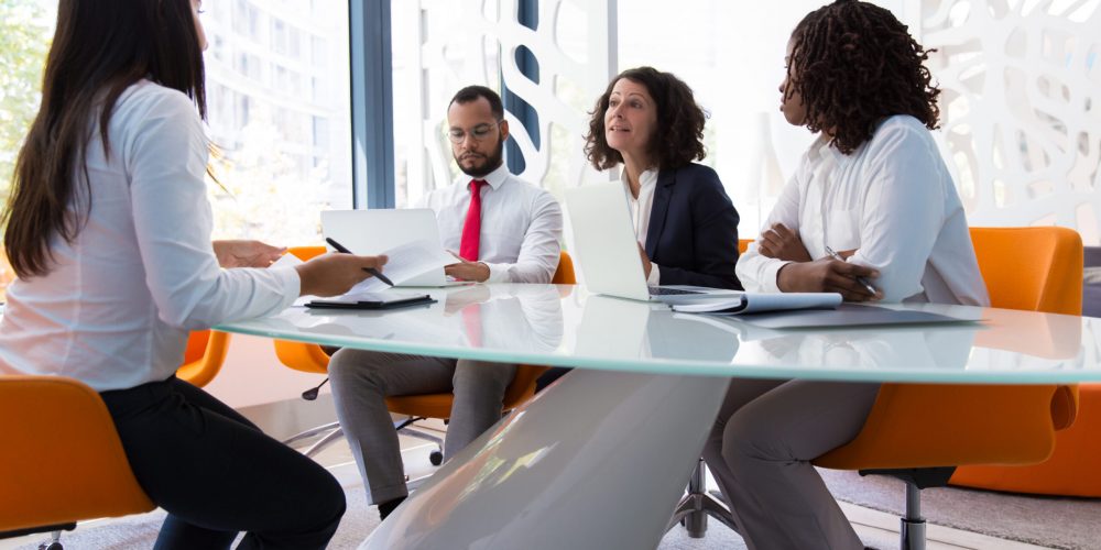 Business leader interviewing job candidate. Business man and women sitting at conference table, using laptops and talking. Discussion agreement concept